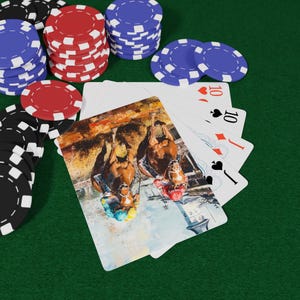 May include: A poker set featuring playing cards and casino chips. The playing cards display a watercolour painting of horses. Stacks of red, blue, and black chips are arranged on a green felt surface.
