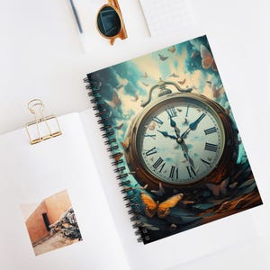 May include: Spiral-bound notebook featuring a surreal illustration of a pocket watch with butterflies. The watch face displays Roman numerals and hands pointing to the time. The cover art has a blue and brown color scheme with a fantasy theme.