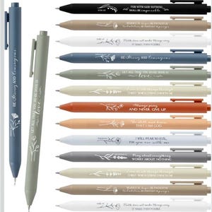 May include: A collection of pens in various colors, including black, beige, white, and blue. Each pen features inspirational quotes and floral designs. The pens have a sleek, modern design with a clip.