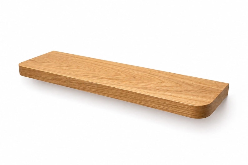May include: A rectangular wooden shelf with rounded corners. The shelf is made of light-colored wood, showcasing a natural grain pattern. It is designed to be mounted on a wall, providing a simple and functional storage solution. The shelf is approximately 30 inches long.