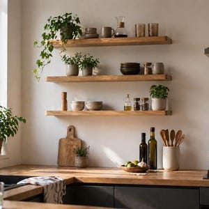May include: A bright kitchen with wooden shelves displaying various kitchenware and potted plants. The shelves are mounted on a white wall above a wooden countertop. A stainless steel faucet and sink are in the foreground.