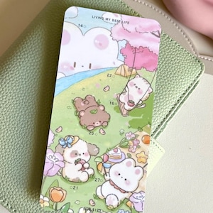 May include: A colorful sticker sheet featuring cartoon bears and the text "LIVING MY BEST LIFE." The sheet has a light green background and is placed on a light green leather-like surface. The bears are engaged in various activities.
