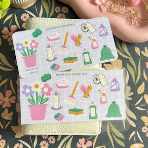 May include: Two rectangular sticker sheets labeled HOUSEHOLD ESSENTIALS featuring a grid pattern and colorful illustrations of cleaning supplies including a potted flower, soap, a broom, rubber gloves, a sponge, a spray bottle, and a trash bag.