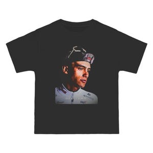 Puede incluir: Camiseta negra con un retrato de un ciclista con gorra y maillot blanco. El maillot tiene el texto "DEL TORO FAB7" impreso. El ciclista mira hacia un lado.