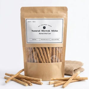 Op de afbeelding: Een bruin papieren zakje met 50 natuurlijke miswak-stokjes voor kruidige mondverzorging. Het etiket vermeldt "ORGIN - INDIA", "RAI SOURAV SHOP", "Natural Miswak Sticks", "Herbal Oral Care", "50 PCS", "PREMIUM QUALITY" en "100% NATURAL".