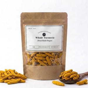 Puede incluir: Un paquete de cúrcuma entera, también conocida como dedos de Haldi secos, con una ventana transparente. Una cuchara de madera contiene una porción de la especia de color amarillo brillante. La etiqueta dice "Whole Turmeric".