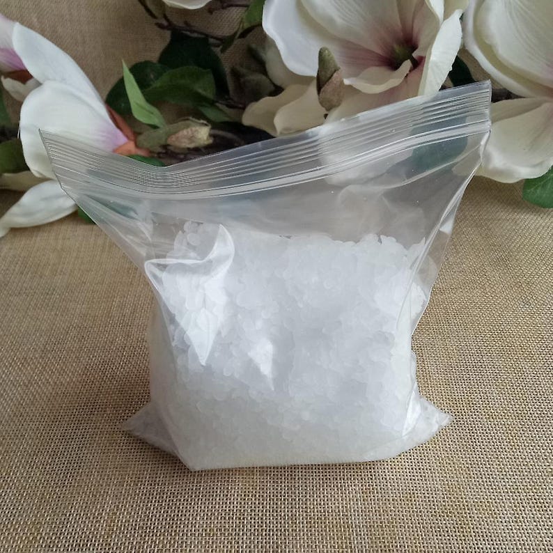 May include: A clear plastic resealable bag filled with small, white, irregular-shaped solid granules. The bag features a horizontal zip-lock closure at the top and contains a granular substance that appears uniform in color and texture throughout.