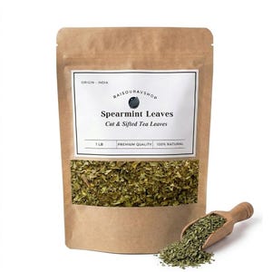 May include: A brown paper bag of spearmint leaves with a clear window, a wooden scoop, and a pile of leaves. The bag has a white label with text that reads "Spearmint Leaves, Cut & Sifted Tea Leaves, 1 LB, Premium Quality, 100% Natural."