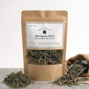 May include: A brown paper bag containing Bhringraj Herb, Dried Eclipta Alba Leaves. A small heap of the herb is in front of the bag, with more spilling out. A scoop and hessian sack are also visible.