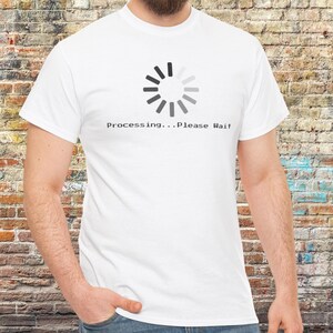 May include: White t-shirt with a grey circular loading graphic and the text "Processing...Please Wait". The shirt is made of a soft material. The design is printed on the front.