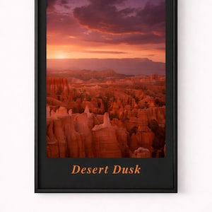 Puede incluir: Impresión enmarcada de un paisaje desértico al anochecer. La imagen presenta una vibrante puesta de sol con tonos de naranja, rojo y morado sobre un cañón. Las palabras "Desert Dusk" están impresas en naranja en la parte inferior del marco negro.