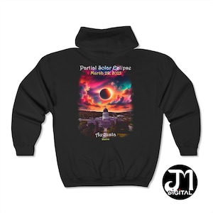 May include: Black hooded sweatshirt with a graphic of a partial solar eclipse over the state capitol building in Augusta, Maine. The text reads "Partial Solar Eclipse March 29, 2025 Augusta Maine".