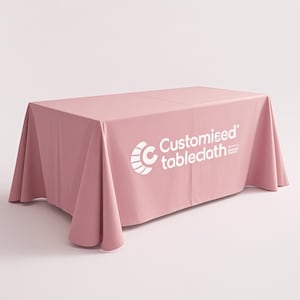 May include: A light pink tablecloth with the text "Customised tablecloth" in white. The tablecloth is draped over a rectangular table, with the edges hanging down. The logo is on the right side of the tablecloth.