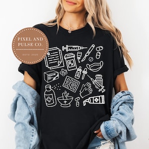 May include: Black t-shirt featuring a white outline design of medical supplies, including syringes, pills, and prescription symbols. The shirt also has the text "PIXEL AND PULSE CO. ESTD. 2025" in a brown circle.