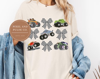 Könnte beinhalten: Cremefarbenes T-Shirt mit einer farbenfrohen Grafik von Monstertrucks und karierten Schleifen. Das Design umfasst verschiedene Monstertrucks in Orange, Grün, Rot und Lila. Das Shirt trägt auch den Text "Pixel and Pulse Co. Estd. 2023".