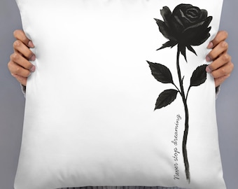 Almofada rosa preta e branca com a frase "nunca pare de sonhar".
