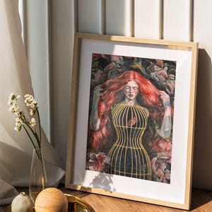 Op de afbeelding: Een ingelijste kunstdruk met een schilderij van een persoon met lang, golvend rood haar, gekleed in een geel kooivormig lijfje over een donker kledingstuk, omringd door donkere bloemelementen. Het kunstwerk zit in een licht houten lijst.