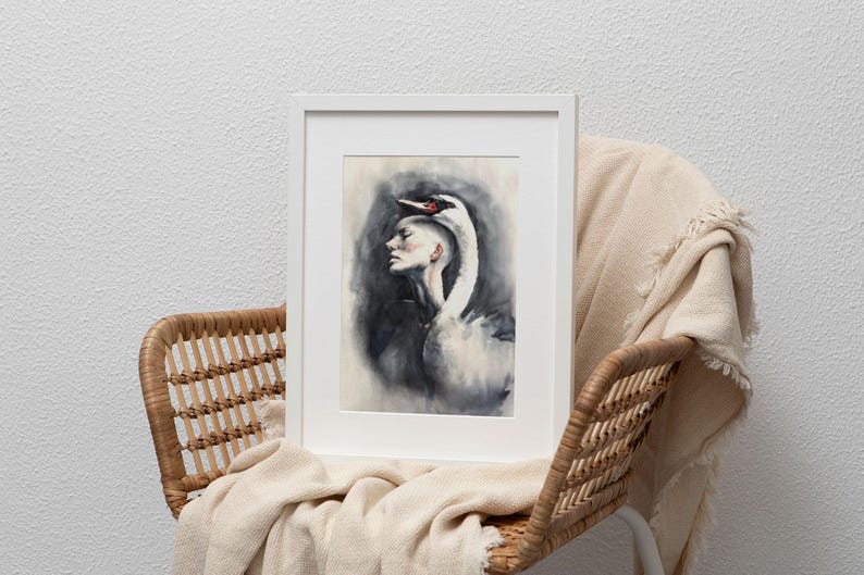 May include: A framed art print featuring a watercolor illustration of a person in profile with a white swan draped over their head. The swan has a black beak with a red patch. The background is a smoky, dark gray wash, all encased in a white frame.