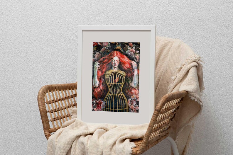 Op de afbeelding: Een ingelijste kunstdruk met een persoon met lang, felrood haar omringd door donkere florale elementen. De persoon draagt een gestructureerd, goudkleurig kooivormig lijfje over een donker kledingstuk, wat een opvallend contrast vormt.