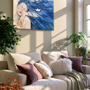 May include: A rectangular wall art print featuring a painting of a person with long, flowing blue hair and closed eyes, resting their head on an arm. A small white paper boat is nestled within the hair. The artwork is displayed in a living room setting.