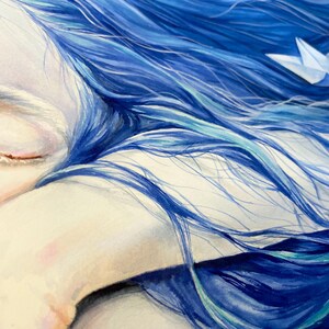 May include: A painting of a face with closed eyes resting on an arm, surrounded by flowing, vibrant blue hair. A small, white paper boat is nestled within the strands of hair, creating a contrast against the deep blue and teal color palette.