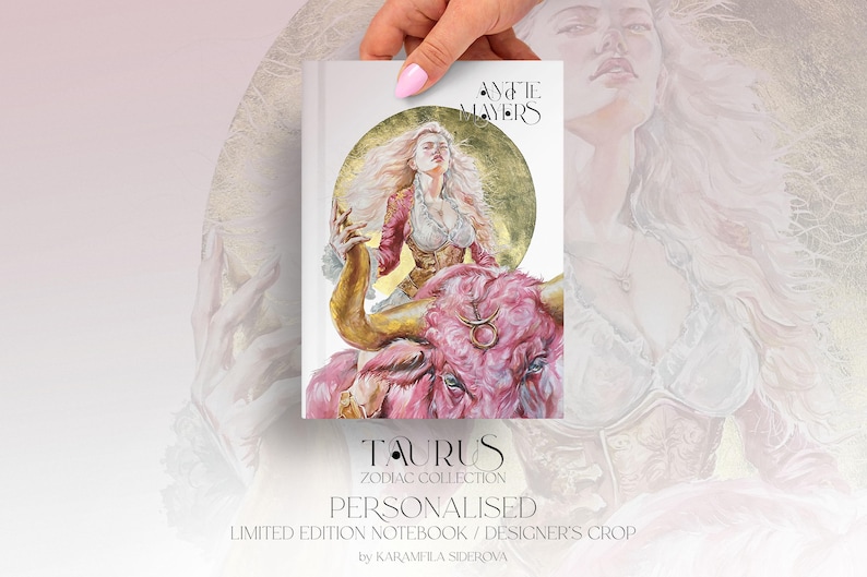 May include: A rectangular notebook featuring an illustration of a person with long blonde hair riding a pink bull against a gold circular background. The text reads "ANATIE MAYERS", "TAURUS", "ZODIAC COLLECTION", "PERSONALISED", "LIMITED EDITION NOTEBOOK", and "DESIGNER'S CROP".
