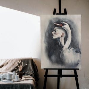 May include: A vertical canvas painting on a black easel depicting a profile view of a person with a shaved head, with a large white swan draped over their head and shoulders. The artwork features soft gray and black watercolor-style shading.