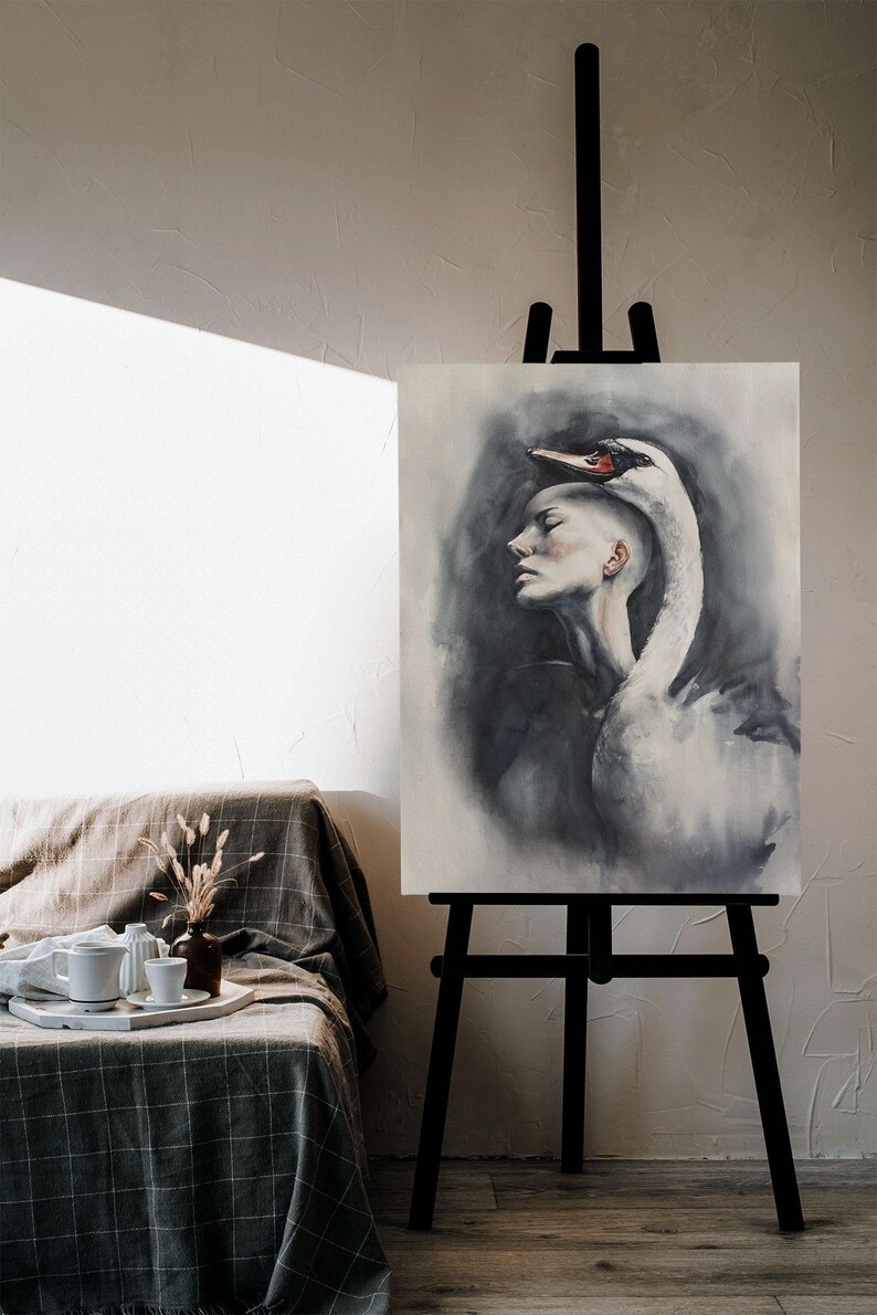May include: A vertical canvas painting on a black easel depicting a profile view of a person with a shaved head, with a large white swan draped over their head and shoulders. The artwork features soft gray and black watercolor-style shading.