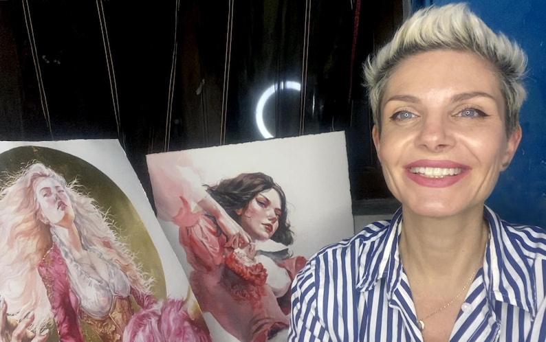 May include: Two rectangular art prints featuring detailed illustrations of figures. The left print depicts a person with long blonde hair in a pink garment against a dark background. The right print shows a person with dark hair in a red top.