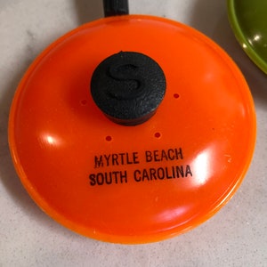 May include: Orange plastic frying pan keychain with a black knob and the text "Myrtle Beach South Carolina".