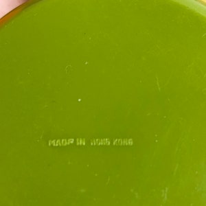 May include: A bright green frying pan with a black handle. The bottom of the pan has the text "MADE IN HONG KONG" printed on it.
