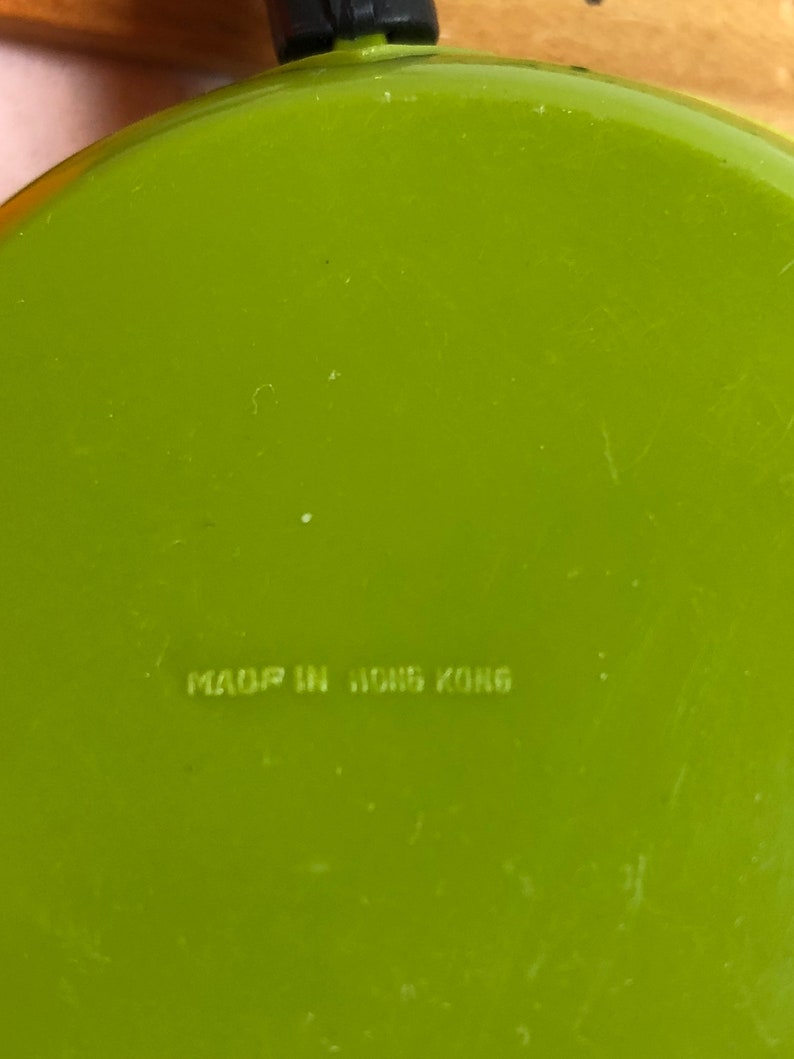 May include: A bright green frying pan with a black handle. The bottom of the pan has the text "MADE IN HONG KONG" printed on it.