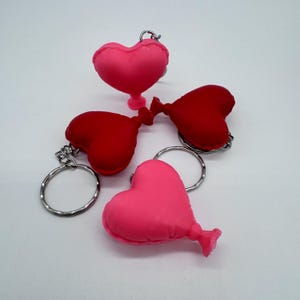 May include: Four heart-shaped balloon keyrings, two pink and two red, with silver key rings.
