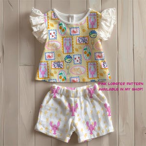 Pu&ograve; includere: Un completo per bambini composto da un top giallo con scollo bianco e maniche a balze, decorato con motivi a francobollo. Gli shorts coordinati sono bianchi con motivi di aragoste rosa e stelle gialle. Il testo "PINK LOBSTER PATTERN AVAILABLE IN MY SHOP!" &egrave; visibile.