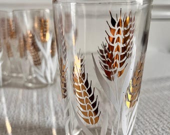 May include: Set of four clear glass tumblers with a white and gold wheat design. The glasses are perfect for everyday use or special occasions.