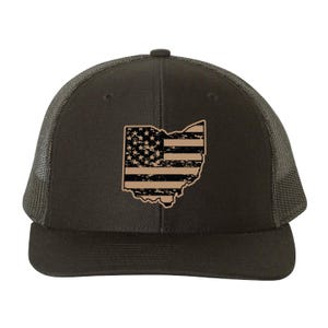 May include: A dark green trucker hat featuring a distressed design of the Ohio state outline with an American flag pattern. The hat has a mesh back and a curved brim.