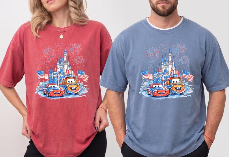 A woman wearing a red t-shirt with a graphic of a castle and fireworks, and a man wearing a blue t-shirt with a graphic of a castle and fireworks.