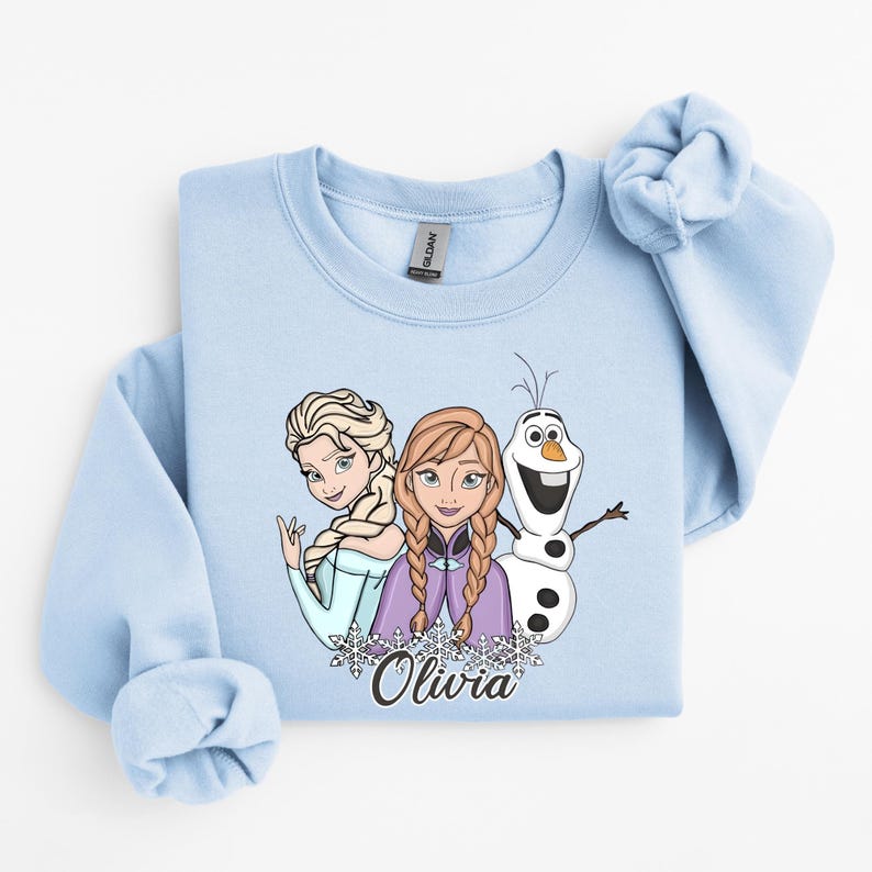 A light blue sweatshirt with a graphic design featuring two cartoon characters and a snowman.