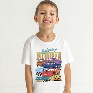 a young boy wearing a white tee shirt with cars on it