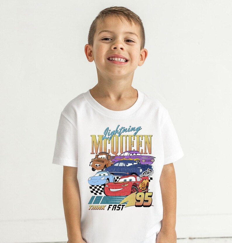a young boy wearing a white tee shirt with cars on it