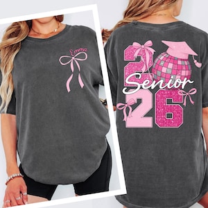 a woman wearing a gray t-shirt with pink ribbons and text on the back.