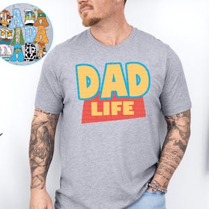 A man wearing a gray t-shirt with the text "DAD LIFE" printed on it.