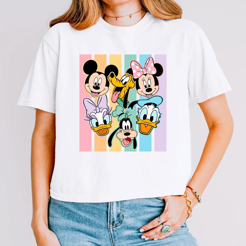A woman wearing a white t-shirt with a colorful graphic of Disney characters on it.