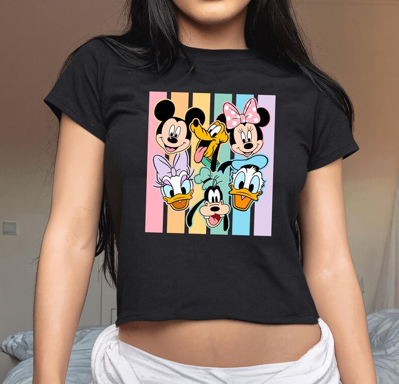A woman wearing a black t-shirt with a colorful graphic of Disney characters on it.