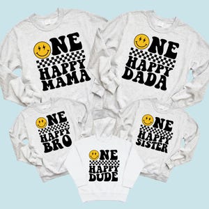 a collection of white sweatshirts with black text and smiley faces printed on them.