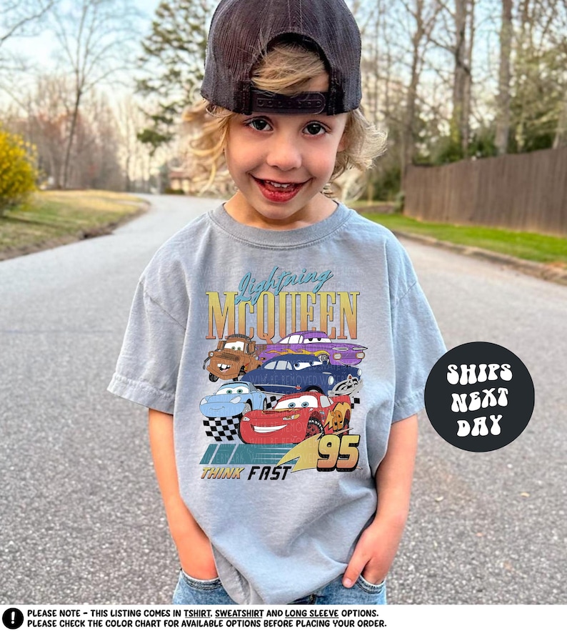 a young boy wearing a gray shirt with cars on it