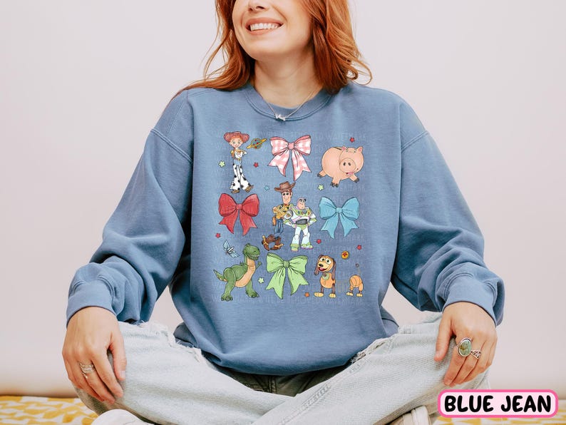 a woman sitting on a bed wearing a blue sweatshirt