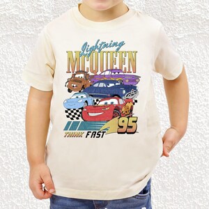 a young boy wearing a white tee shirt with cars on it