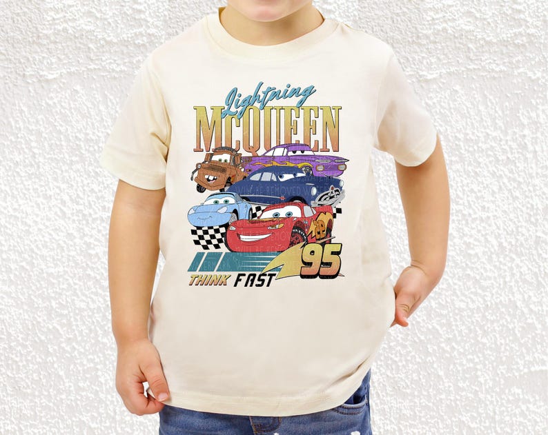 a young boy wearing a white tee shirt with cars on it