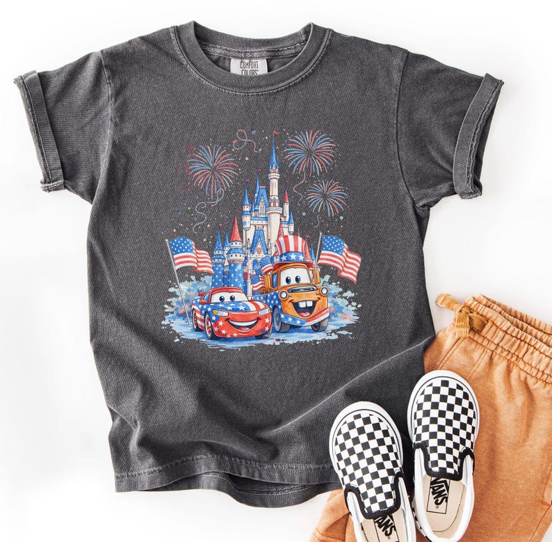 A gray t-shirt with a graphic of a castle and fireworks, along with a pair of checkered shoes, is displayed on a white background.
